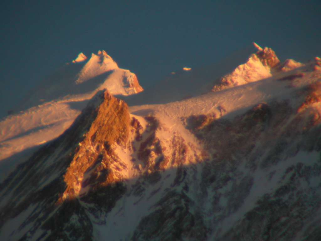 Manaslu 09 10 Manaslu Summit Plateau Close Up At Sunset From Bimtang Tilman wrote in 1950: From this belvedere we looked over the dark forest to the debris of a glacier below and beyond to the cirque at the foot of Manaslu from which it flowed. On the right two sky piercing towers of rock and ice struck us with amazement, almost eclipsing by their savage splendour the calm, monumental mass of Manaslu. From a low snow col the long north ridge of the mountain climbed airily over a bump of the order of 25,000 ft., dropped 1,000 ft., and then rose sharply to a snow plateau. On this remote pedestal, standing well back, stood the summit pyramid.